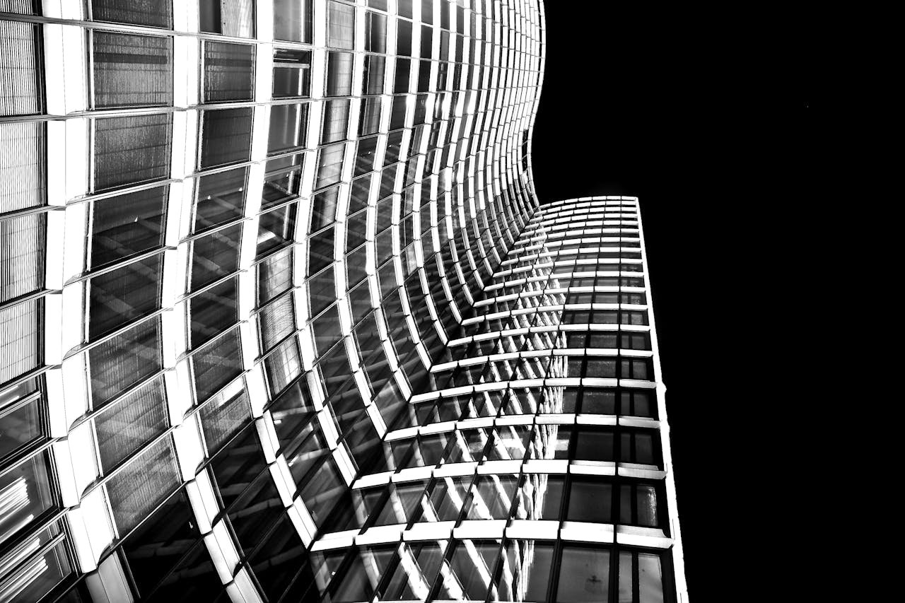 services-04 Striking black and white photo of a modern skyscraper with a curved glass facade shot from a low angle.